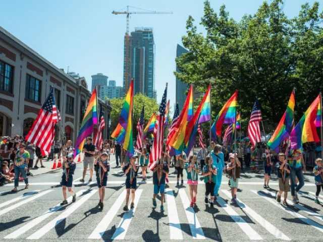 Adults and children hold Pride flags in downtown Seattle