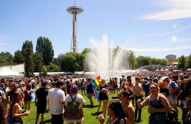 event-pridefest-seattle-center People hold rainbow Pride flags at Seattle Center in front of the Space Needle