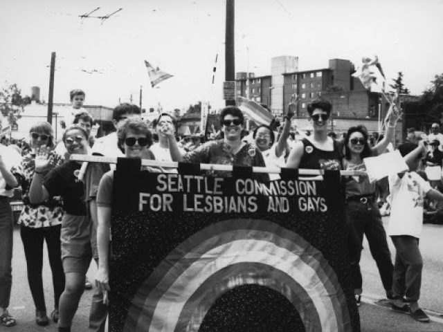 Black and white image of people holding a banner reading 