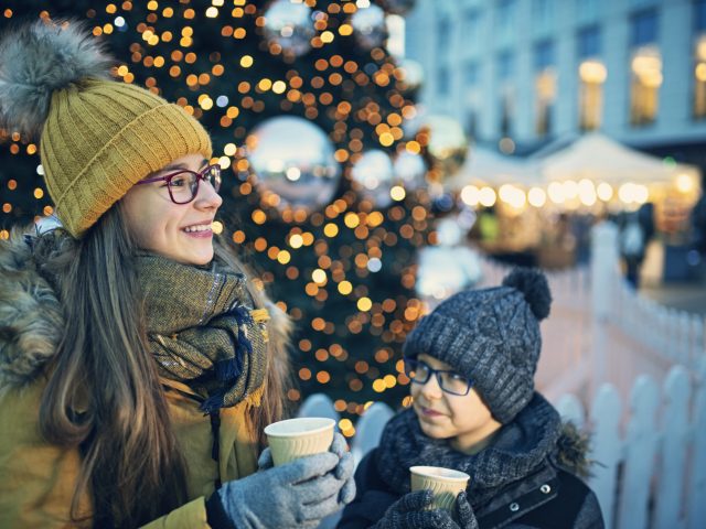 Mother and daughter enjoying a hot drink in front of a Christmas tree