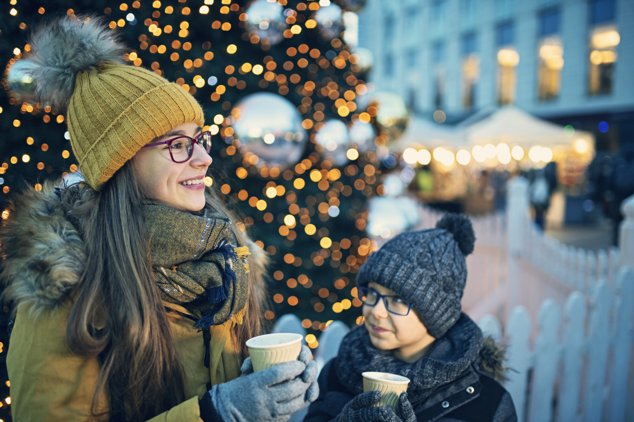 Mother and daughter enjoying a hot drink in front of a Christmas tree