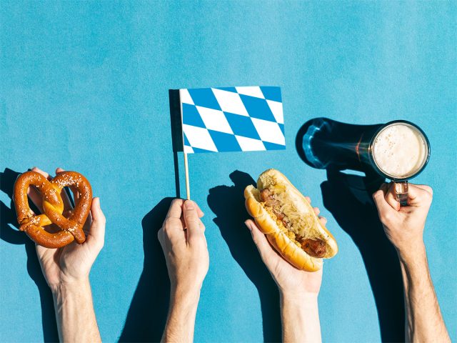 Hands holding snacks, beer and flag on blue background